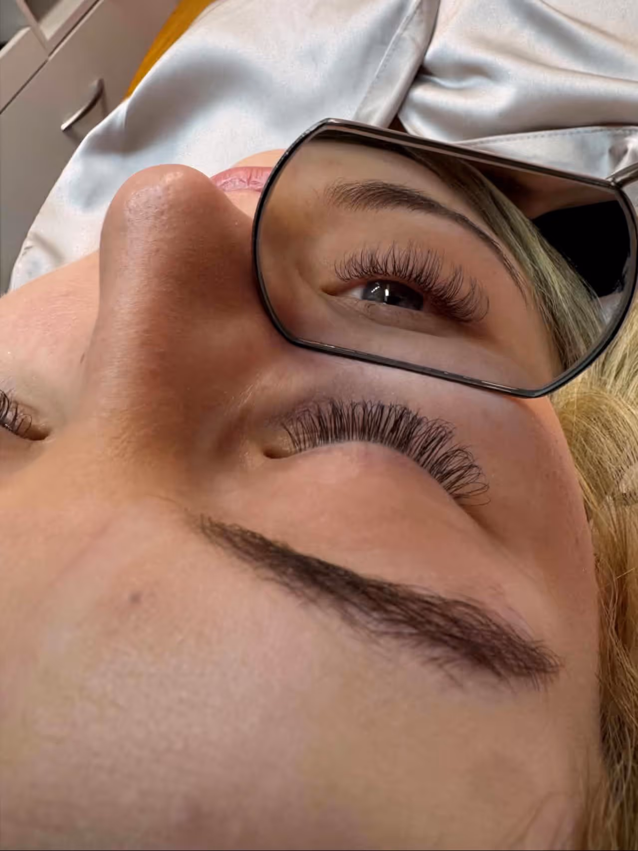 Close-up of a person's face focusing on eyes with long curled eyelashes and thick eyebrows, showing freckles on the skin.