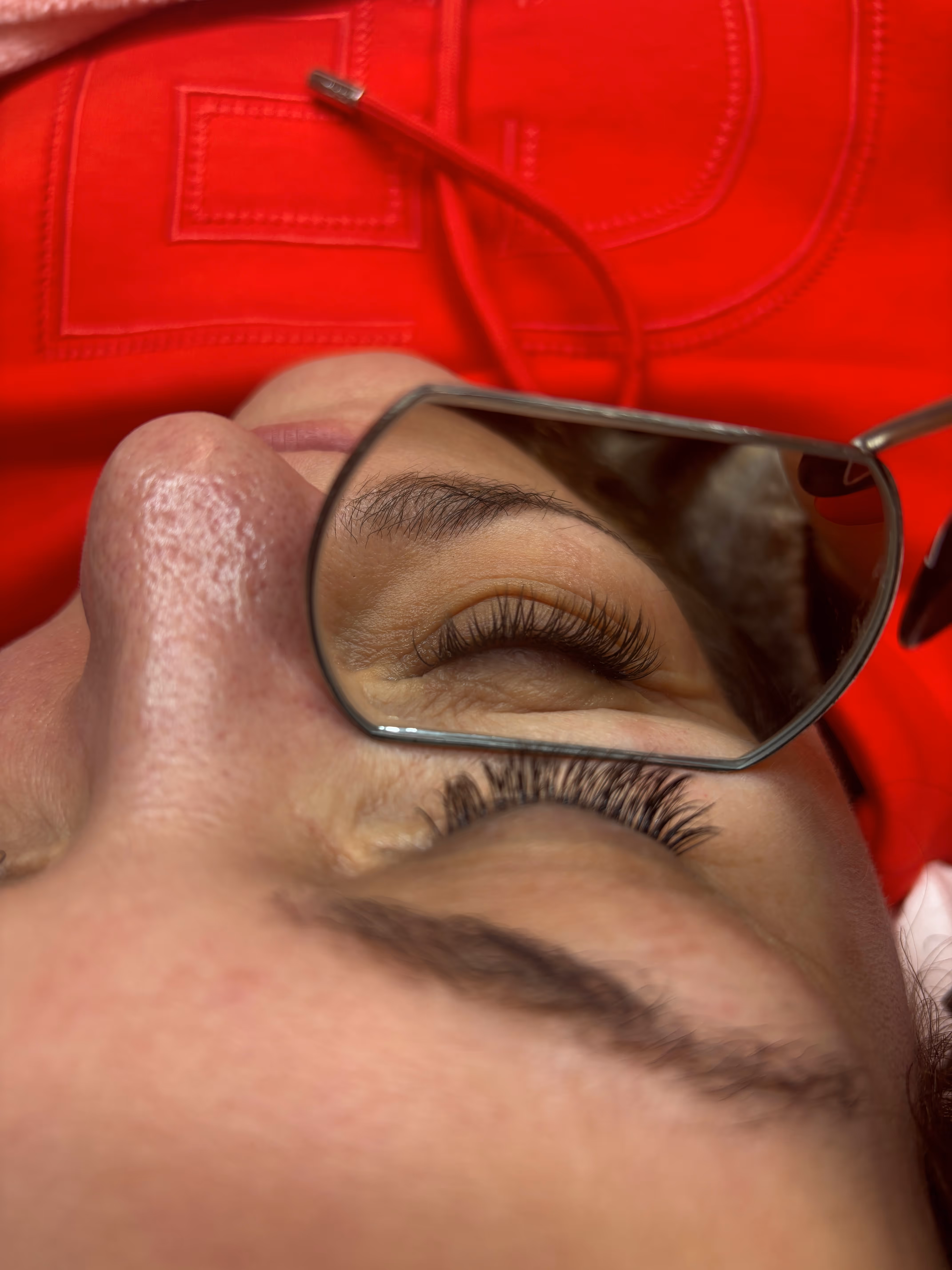 Close-up of a person's face focusing on eyes with long curled eyelashes and thick eyebrows, showing freckles on the skin.