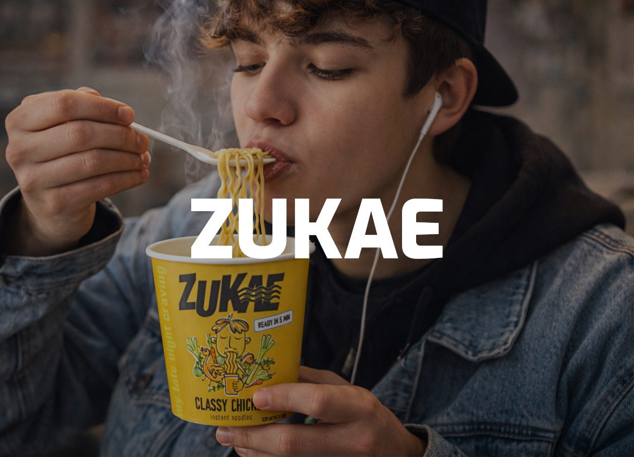 Young person wearing a denim jacket and earphones eating steaming instant noodles from a yellow Zukae cup labeled Classy Chicken.