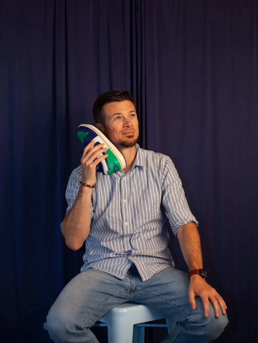 A headshot of Matt, holding his shoe to his ear like a phone