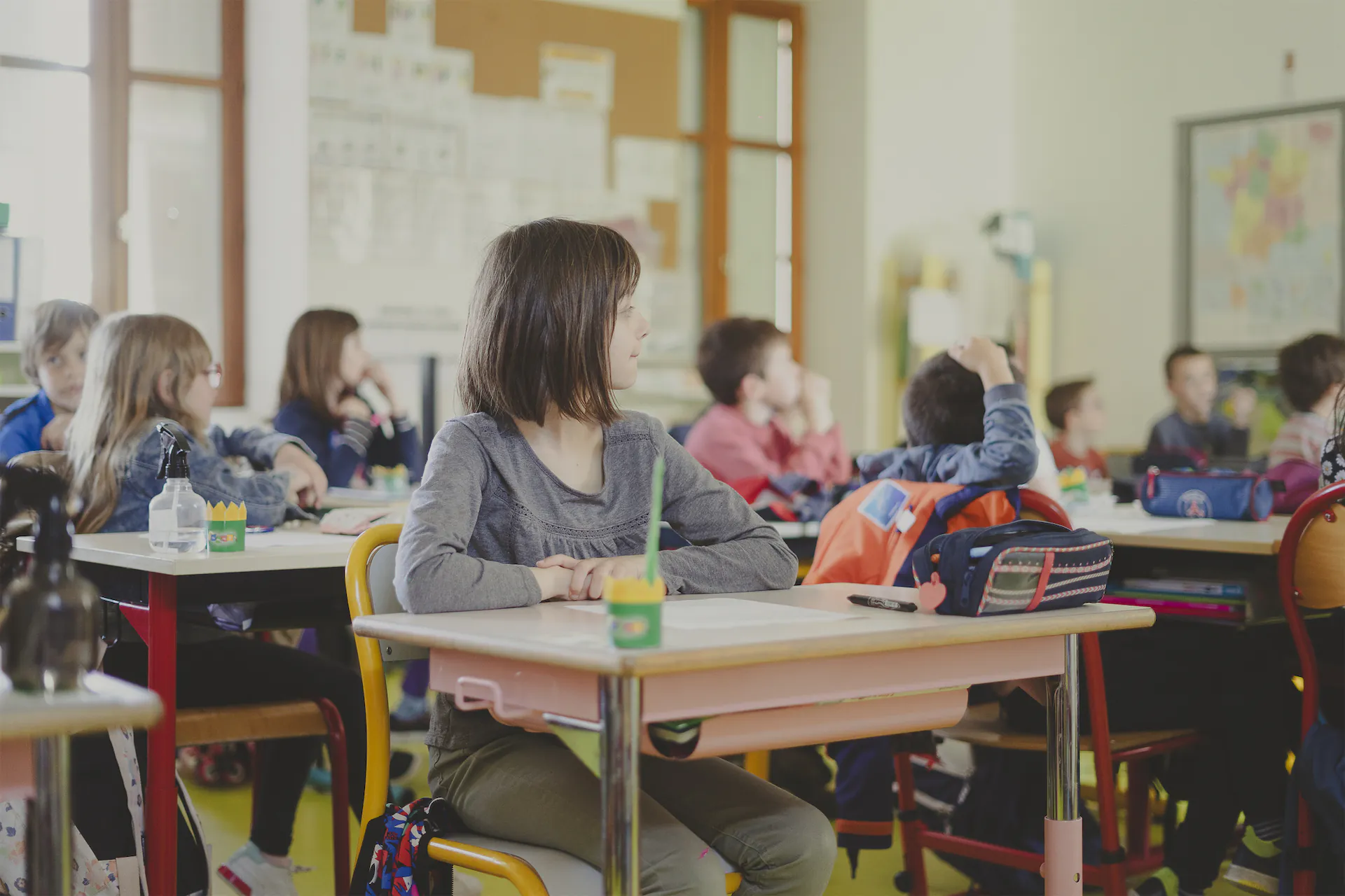 Élèves assis à leurs bureaux dans une salle de classe, attentifs à une leçon.