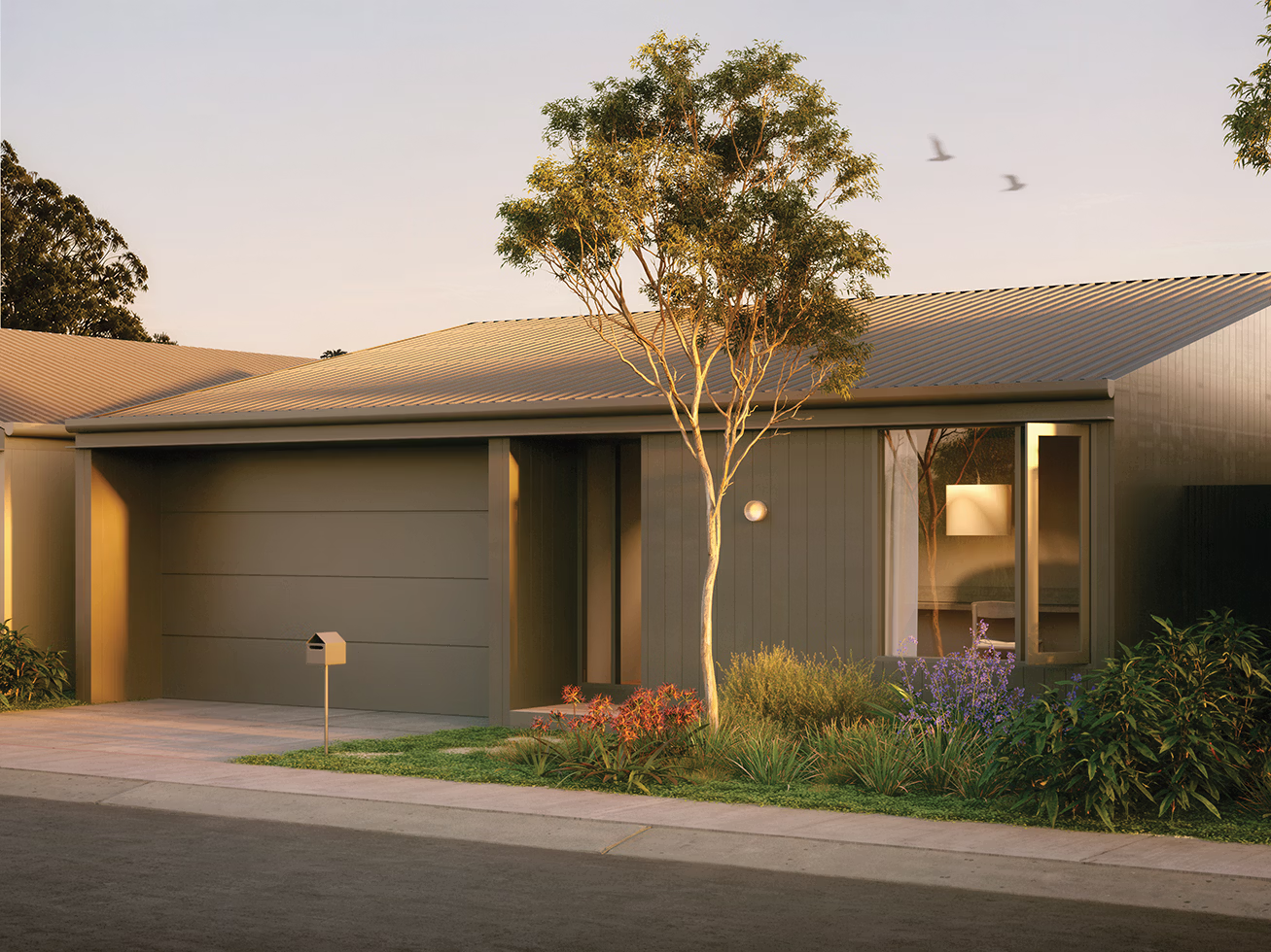 Modern single-story house with a garage, a tree, and a mailbox at sunset.