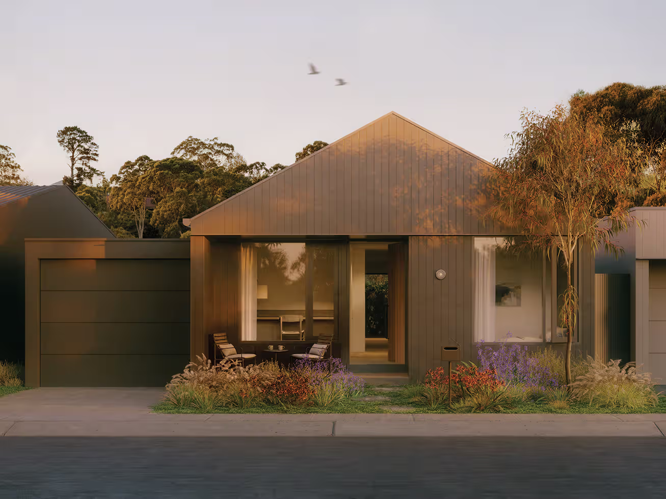 Modern single-story house with dark exterior, garage, front porch seating, and garden at dusk.
