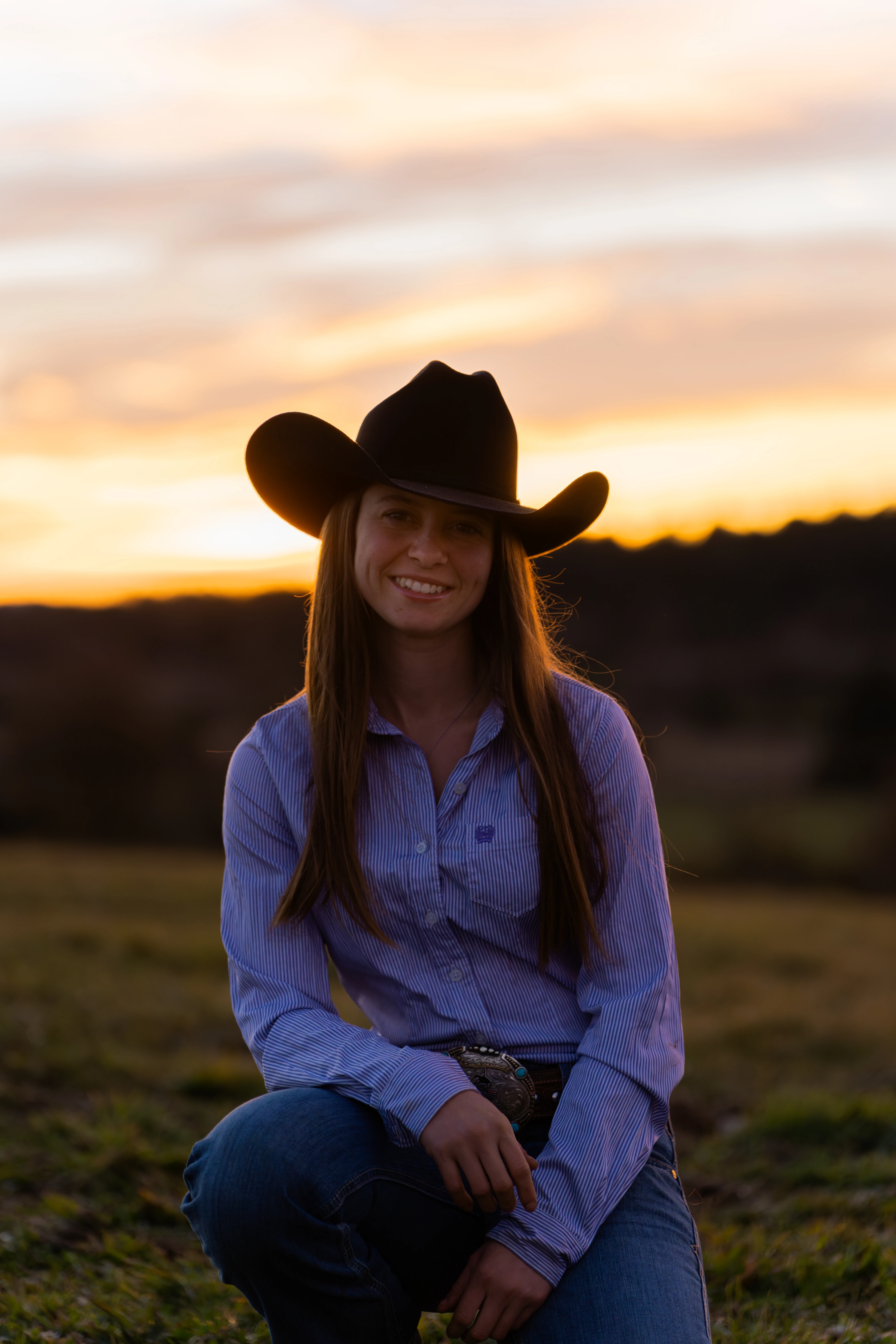Femme souriante portant un bonnet rose et un pull blanc, debout dans la neige avec des arbres en arrière-plan.