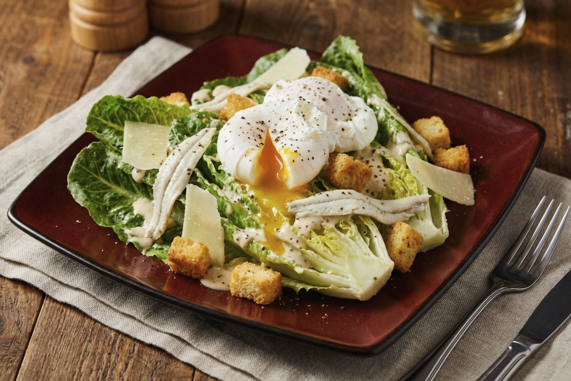 Plated meal of Caesar Salad topped with two poached ggs