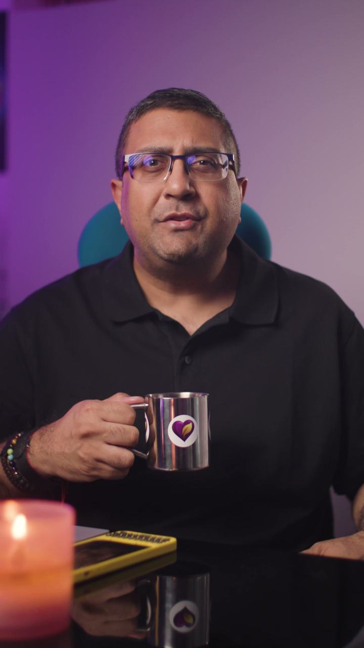 Paraag Amin at his desk in a black shirt, holding a mug