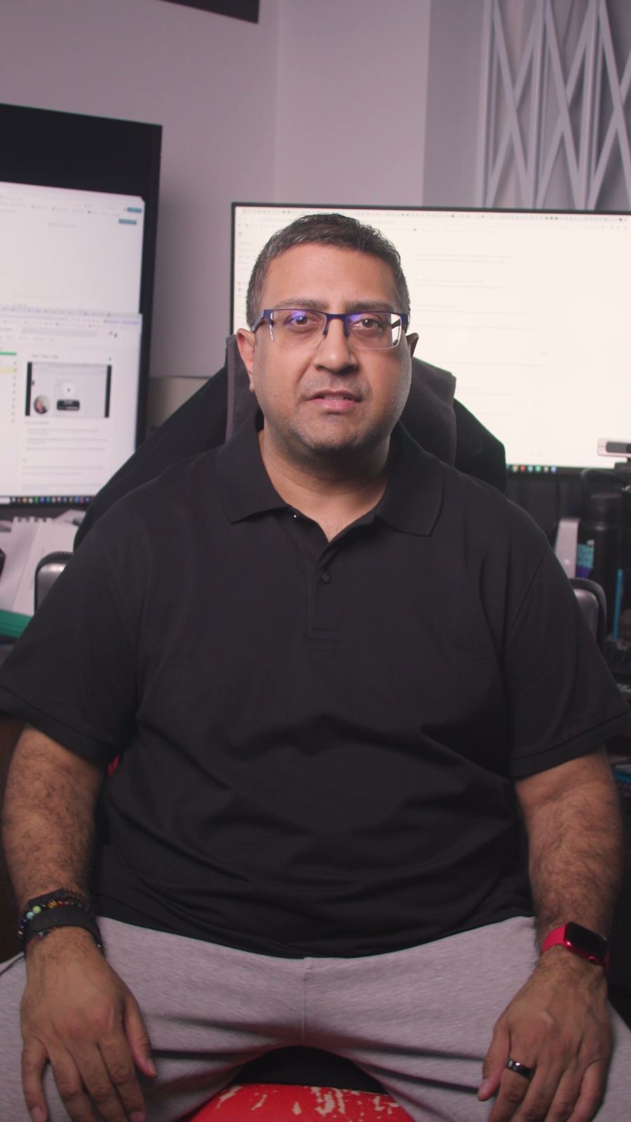 Paraag Amin sitting in his study in a black shirt, in front of two screens