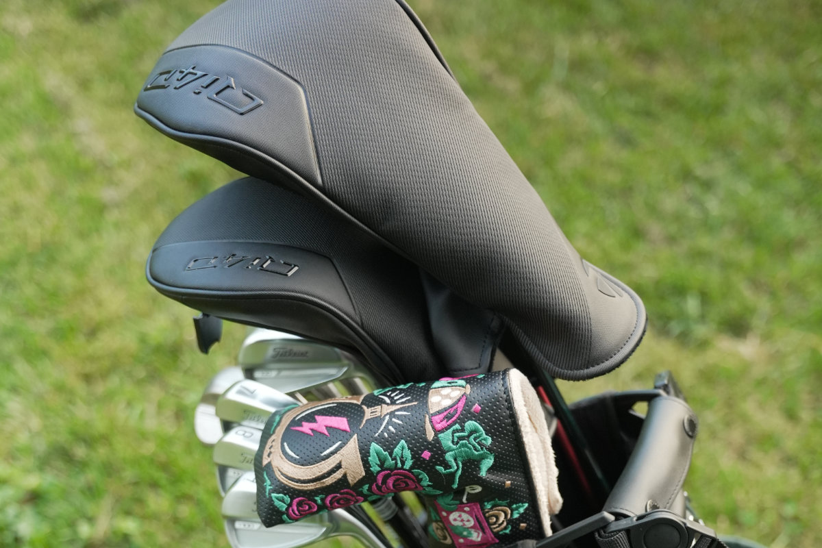 TaylorMade Qi4D driver, 3-wood, and 7-wood with headcovers in a Royal AM golf bag on a grass course