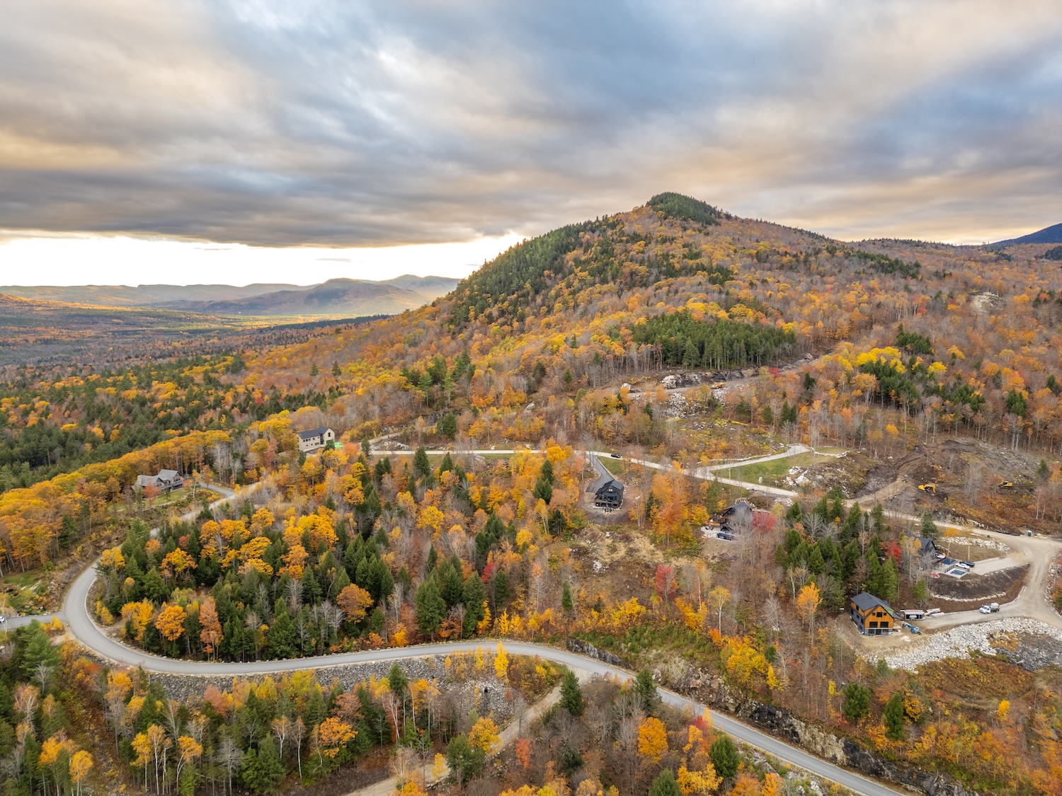 Winding mountain road through fall foliage near Bethel, Maine with forested hills and scenic views