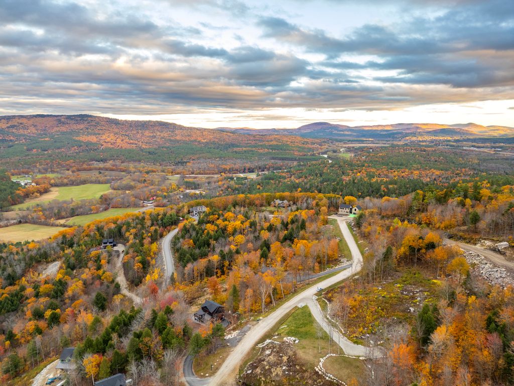 Aerial view of Bethel, Maine surrounded by rolling hills, winding roads, and vibrant fall foliage