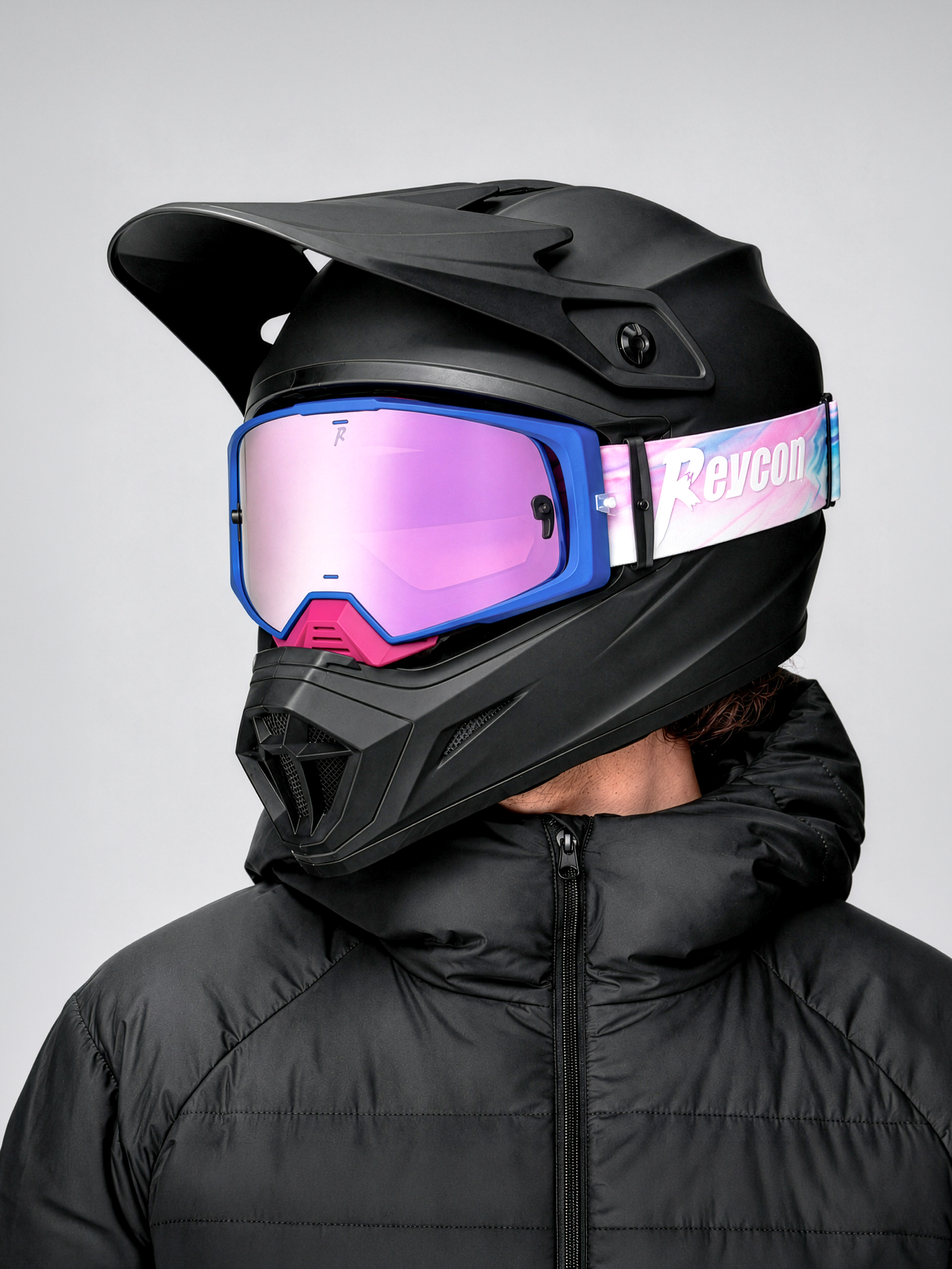 Person portant un casque noir avec lunettes de protection violettes et veste noire zippée.