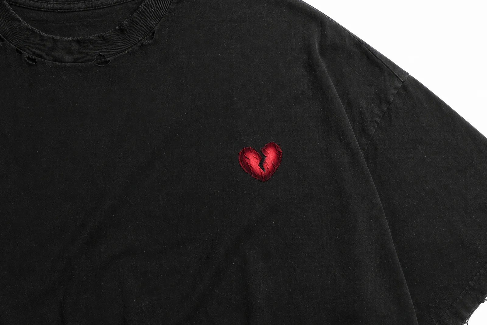 Close-up of the embroidered red broken heart on distressed fabric