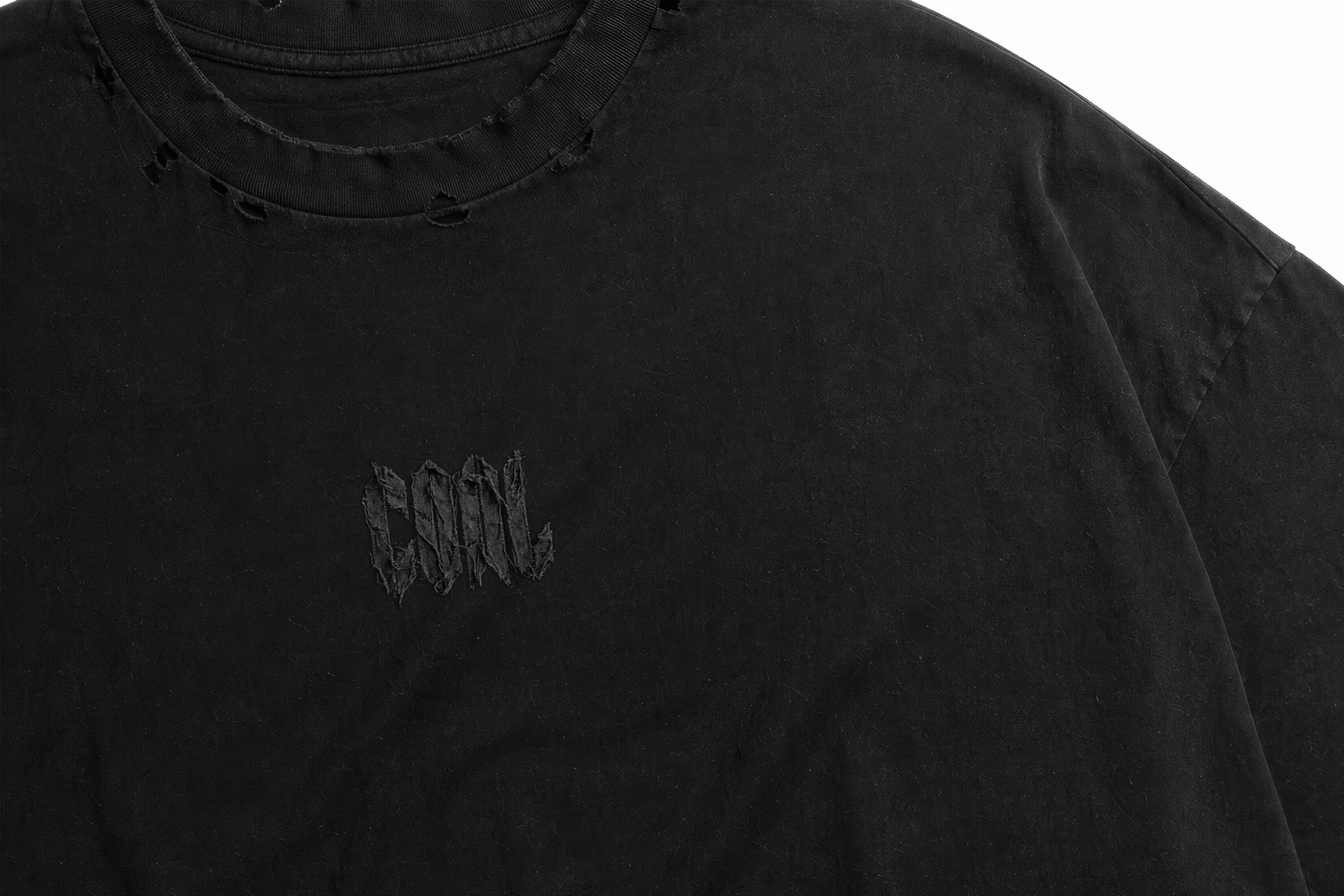 Close-up of the tonal embroidered COAL logo on distressed fabric