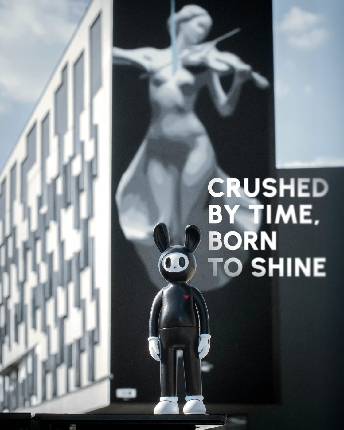 Coally in front of a mural, CRUSHED BY TIME, BORN TO SHINE on the wall behind him.