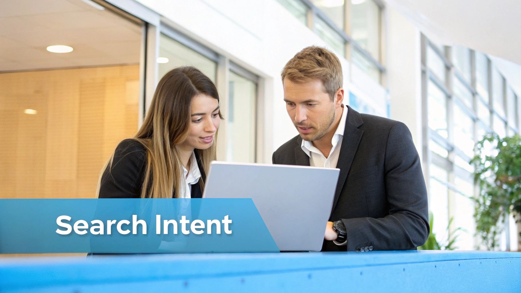 Two business professionals collaborating on a laptop, discussing digital strategies in a modern office setting.