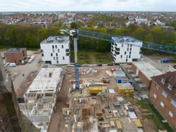 Bau einer Wohnanlage mit zwei fast fertigen mehrstöckigen Gebäuden und einem Baukran in der Mitte.