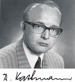 Schwarzweiß-Porträt eines älteren Mannes mit Brille, Anzug und Krawatte, darunter eine Unterschrift.