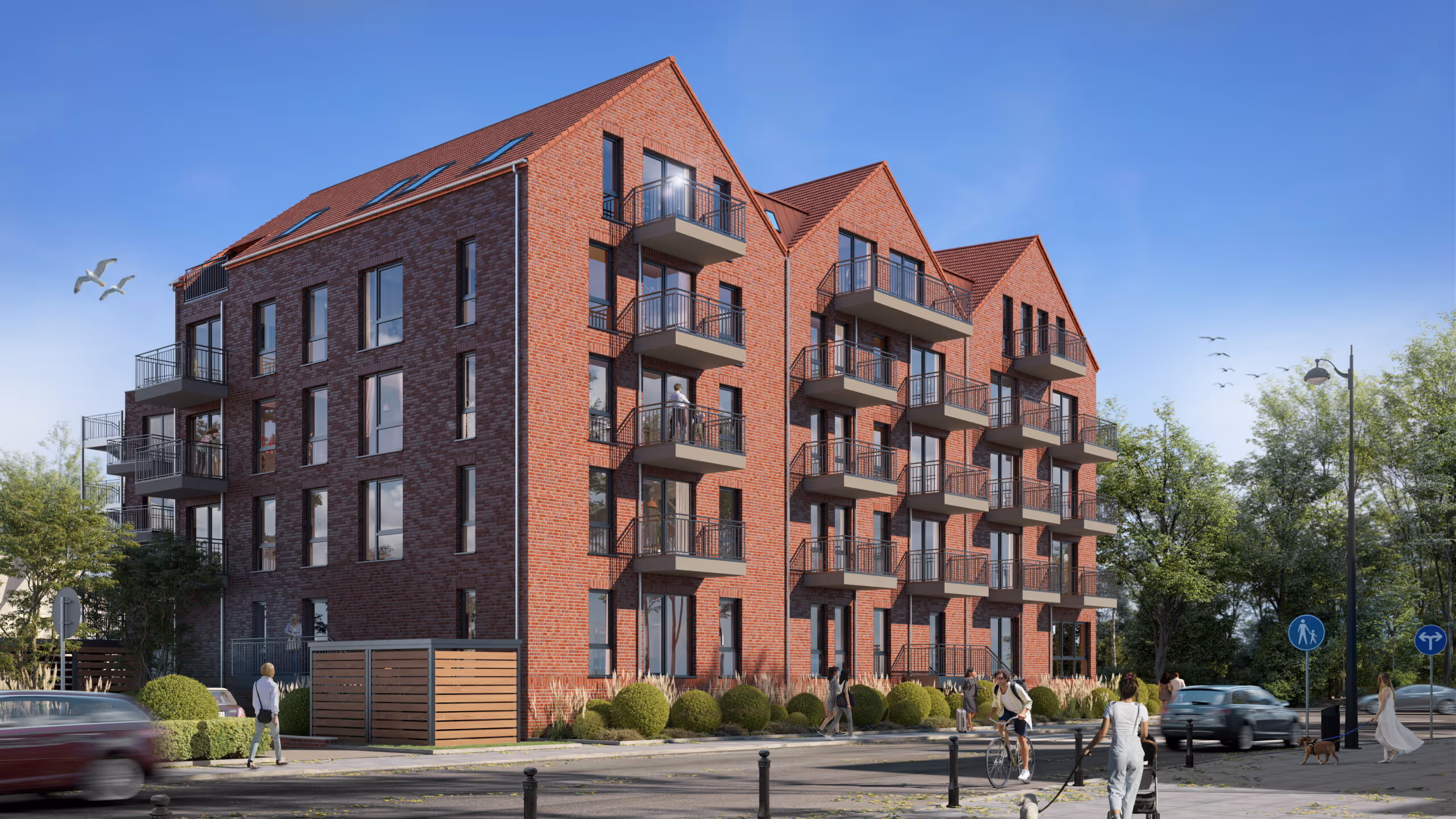 Modernes rotes Backsteinhaus mit Balkonen, umgeben von Büschen, auf einer Straße mit Fußgängern, Radfahrern und parkenden Autos.