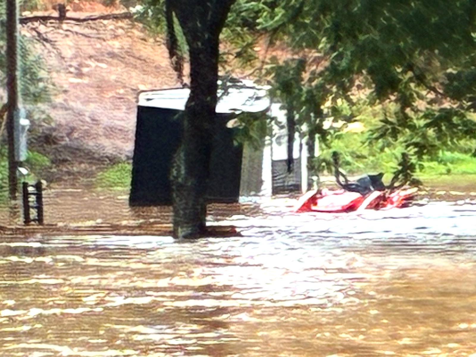 Floodwater covering the yard at Crooked Oak Farm, Carroll County VA, on the morning of August 2, 2026, submerging a shed door and a parked utility vehicle.