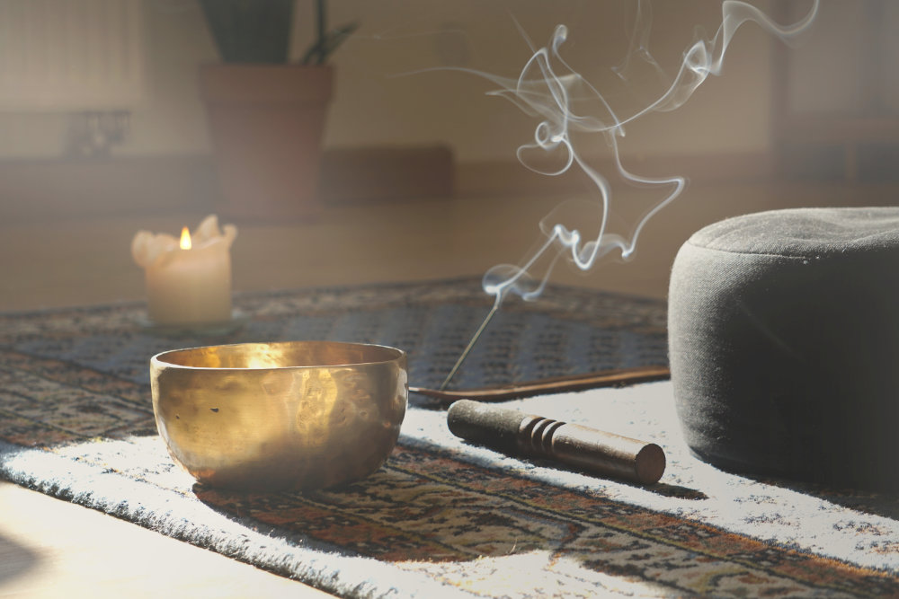 Tibetan singing bowl with mallet, burning incense and candle creating a calm atmosphere for reiki and meditation practice