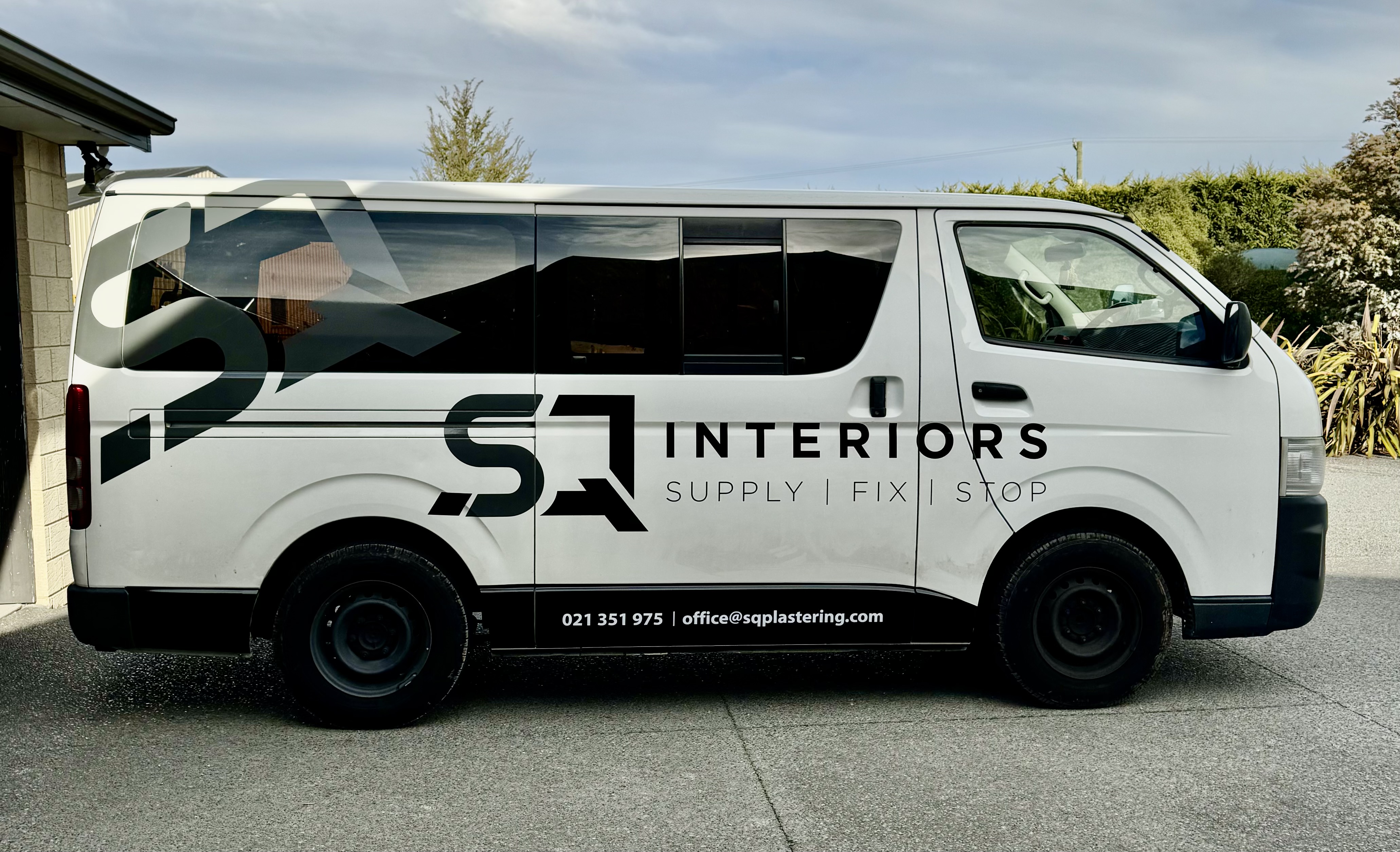 The white SQ Plastering Van passed outside a garage in a driveway.