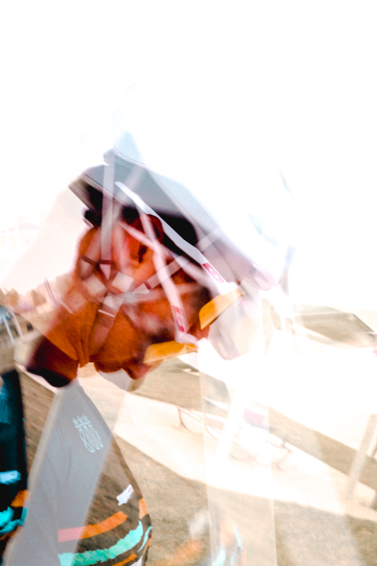 Close-up of a cyclist wearing a helmet and glasses, with motion blur effect.