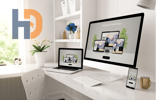 Modern office desk with a desktop computer, laptop, and smartphone all displaying responsive web design, next to a gold mug and potted plant.