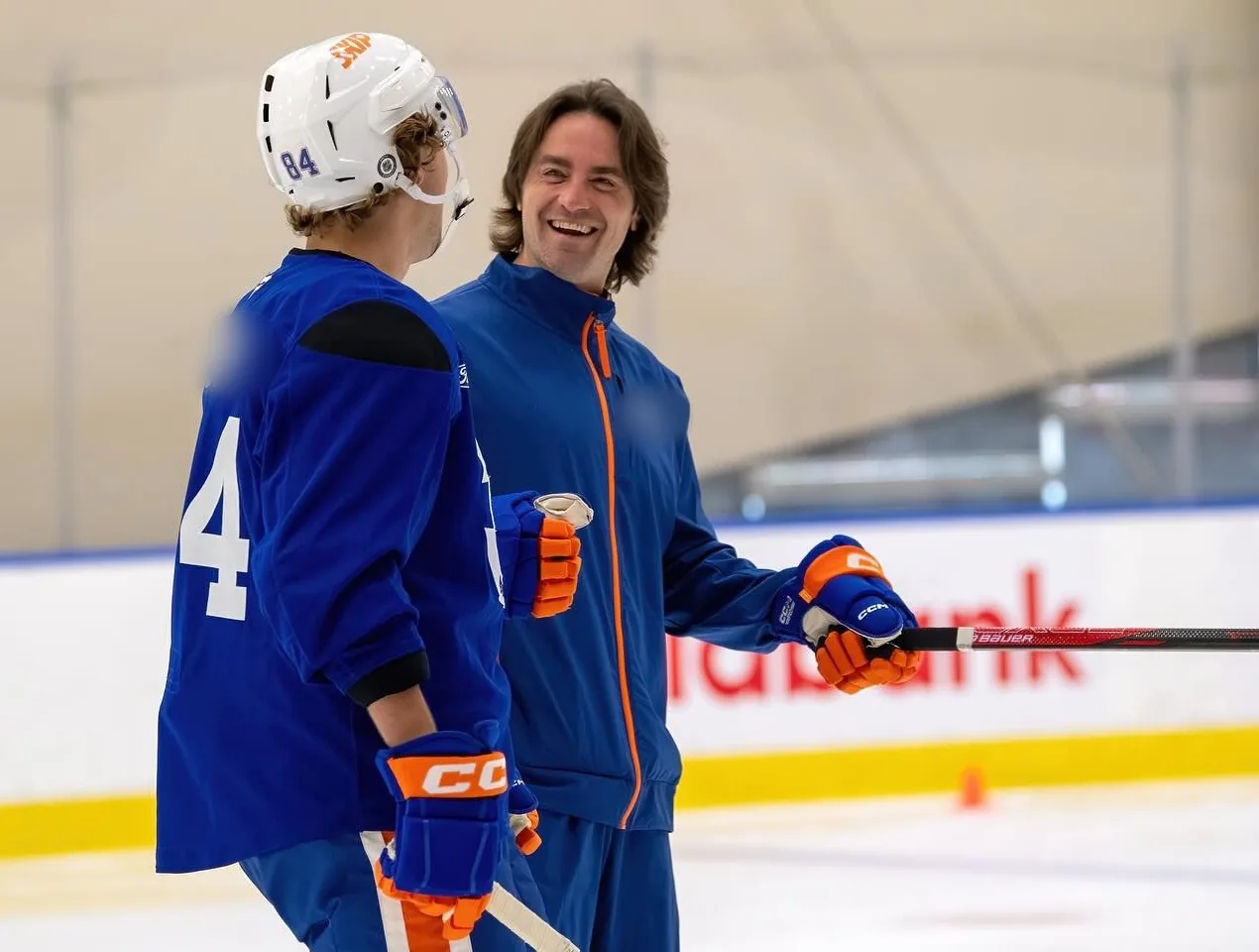 Coach Vinny Malts smiling and talking with a player on the ice