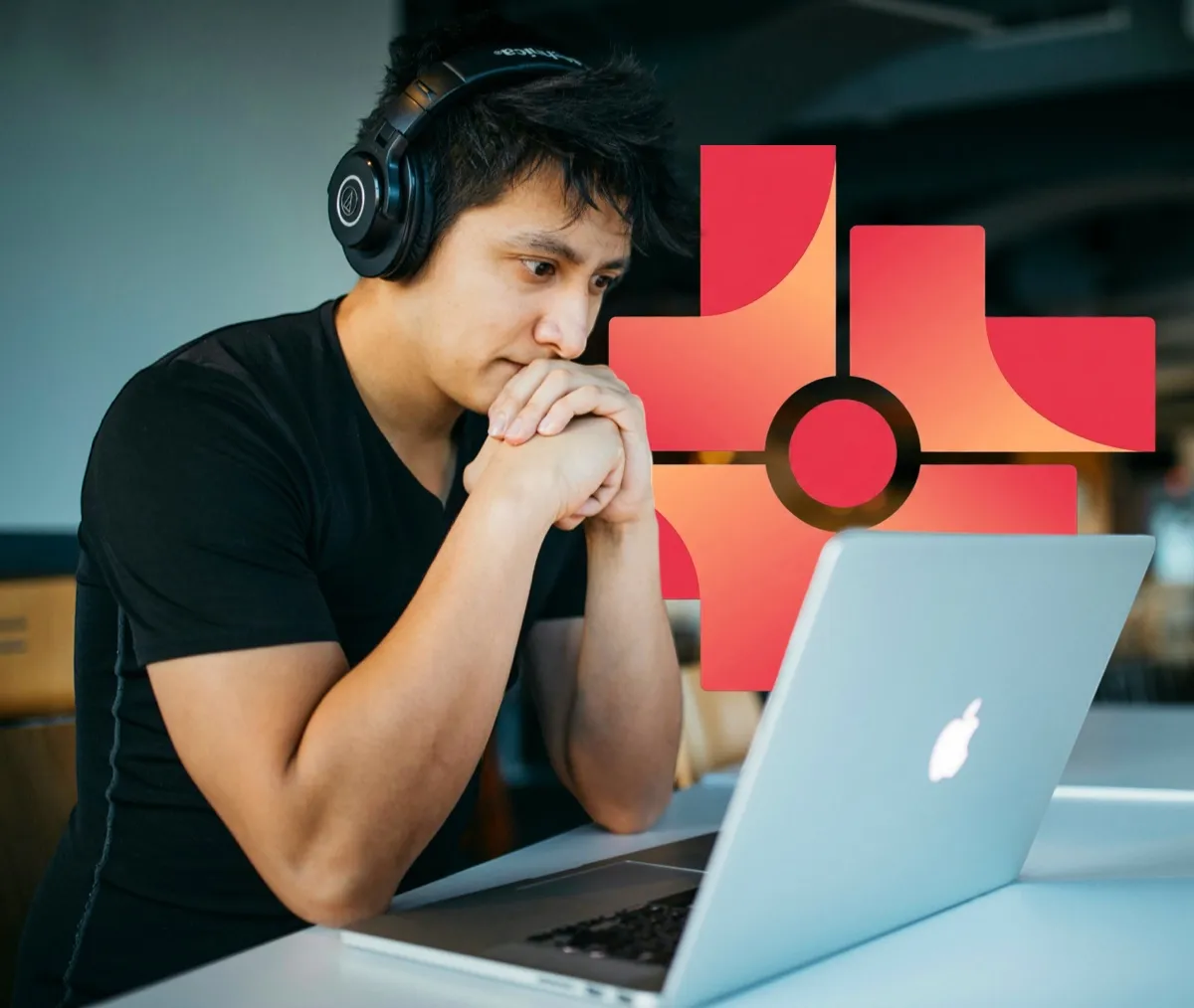 Young man wearing headphones intently looking at a laptop with a stylized red and orange cross symbol in the background.