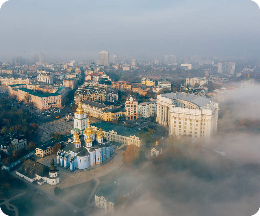 Пам'ятник «Батьківщині» у Києві з українським тризубом на щиті, що височіє на тлі туманного пейзажу.