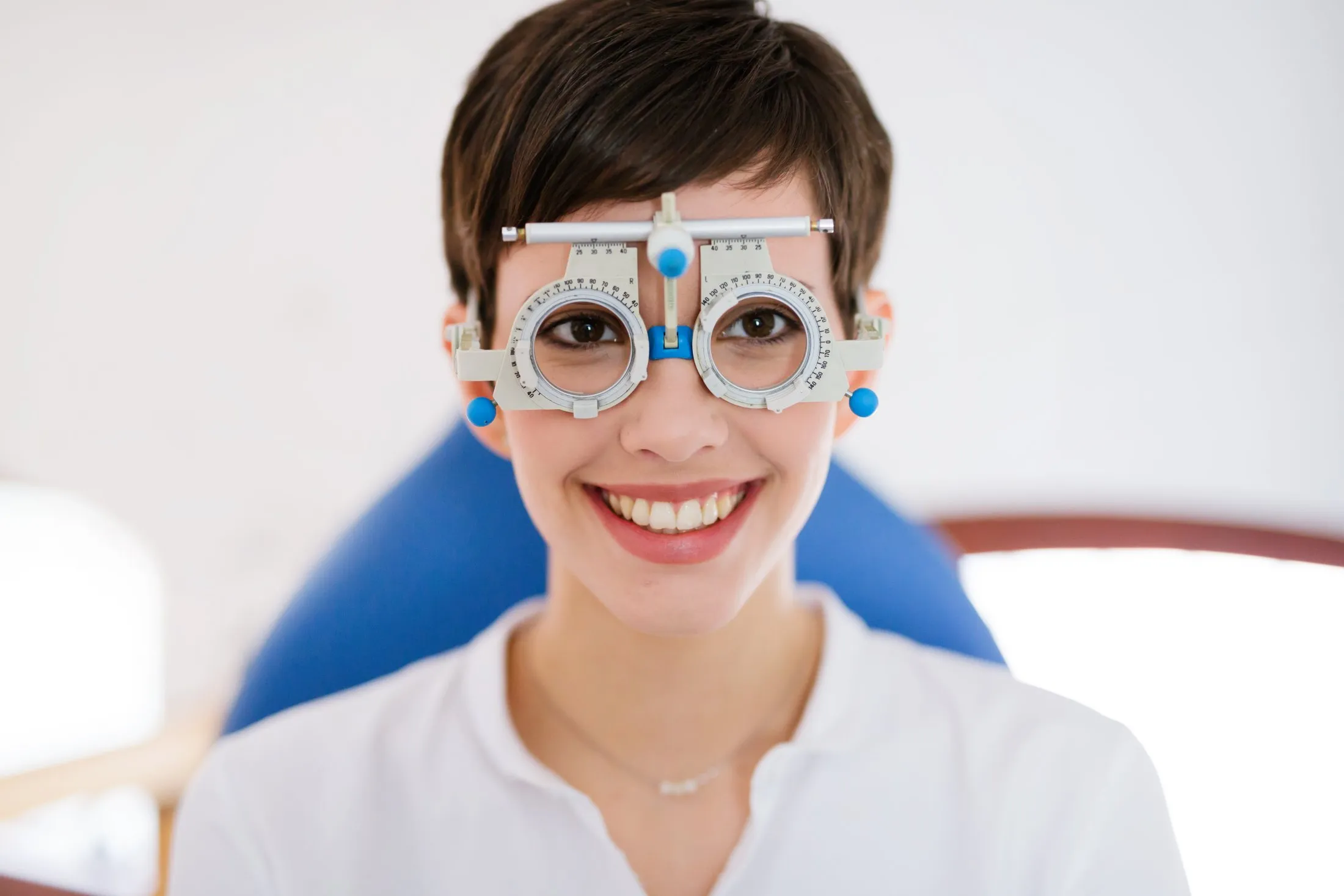 Child wearing optical phoropter eye examination equipment, smiling at camera