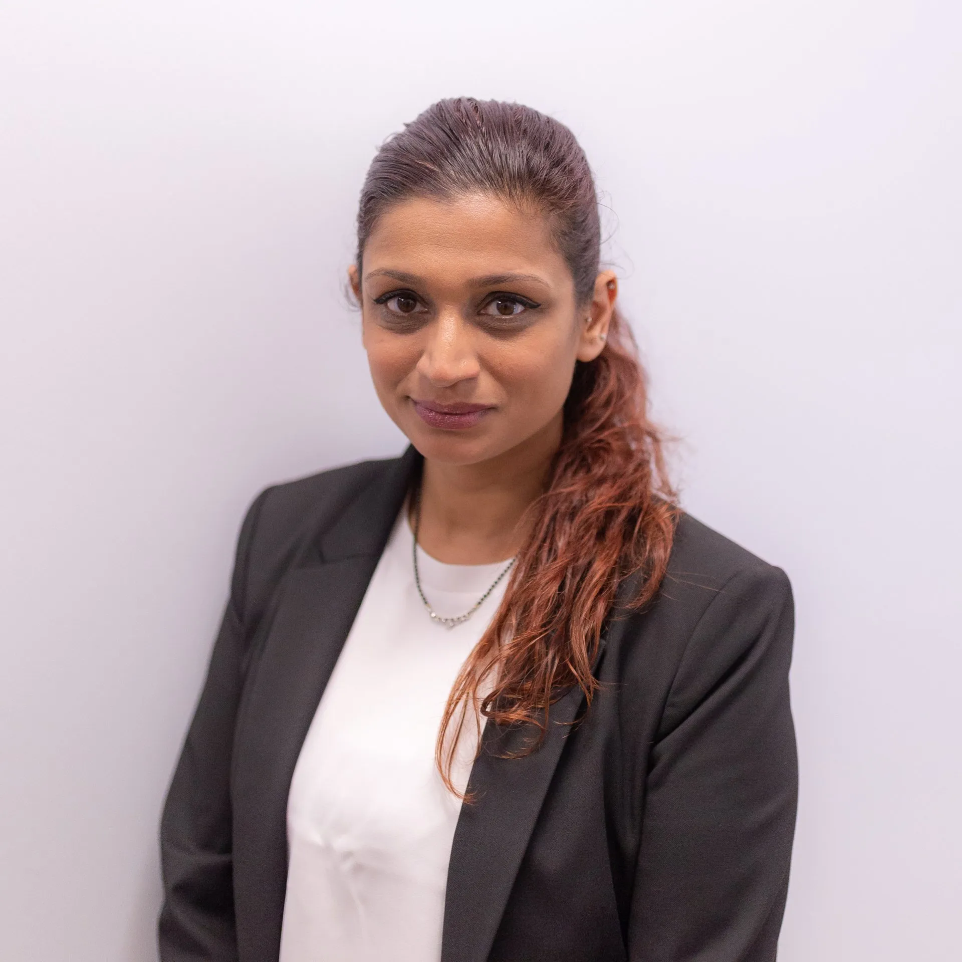 Professional portrait of woman with reddish-brown hair wearing black blazer and white top