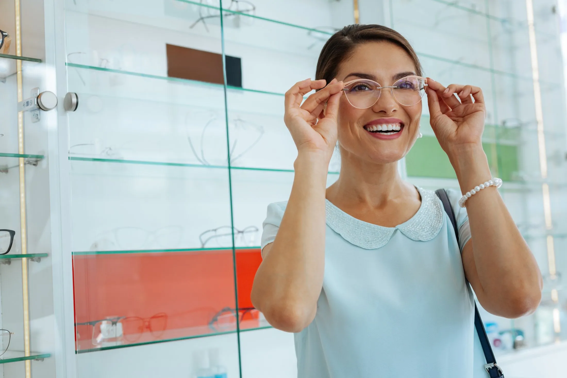 Happy woman trying on clear eyeglasses in modern optical shop display