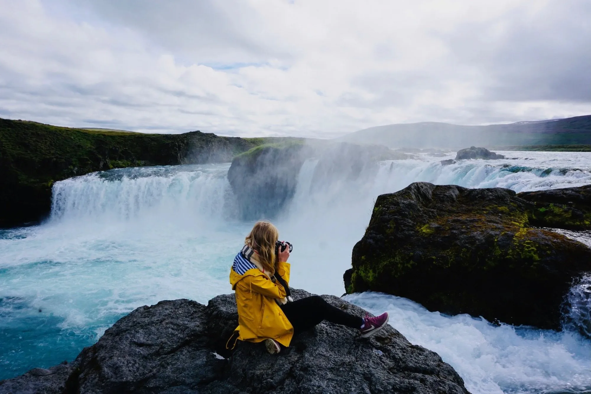 Frau fotografiert einen Wasserfall in Island