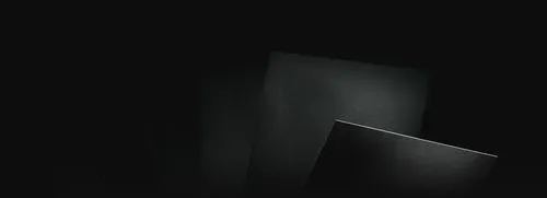 Close-up of overlapping dark textured sheets illuminated by a subtle light gradient.