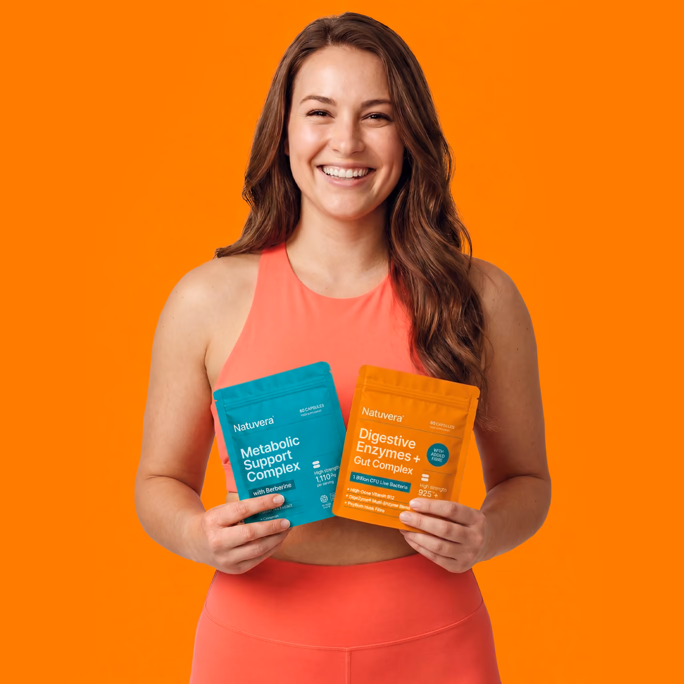 Smiling woman in coral activewear holding two Nutuvera supplement packs against orange background.