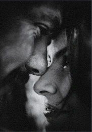 Close-up black and white photo of a man and woman facing each other, their noses nearly touching.