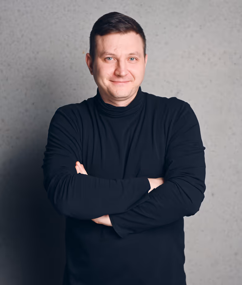  Smiling man in dark blazer in front of plain wall