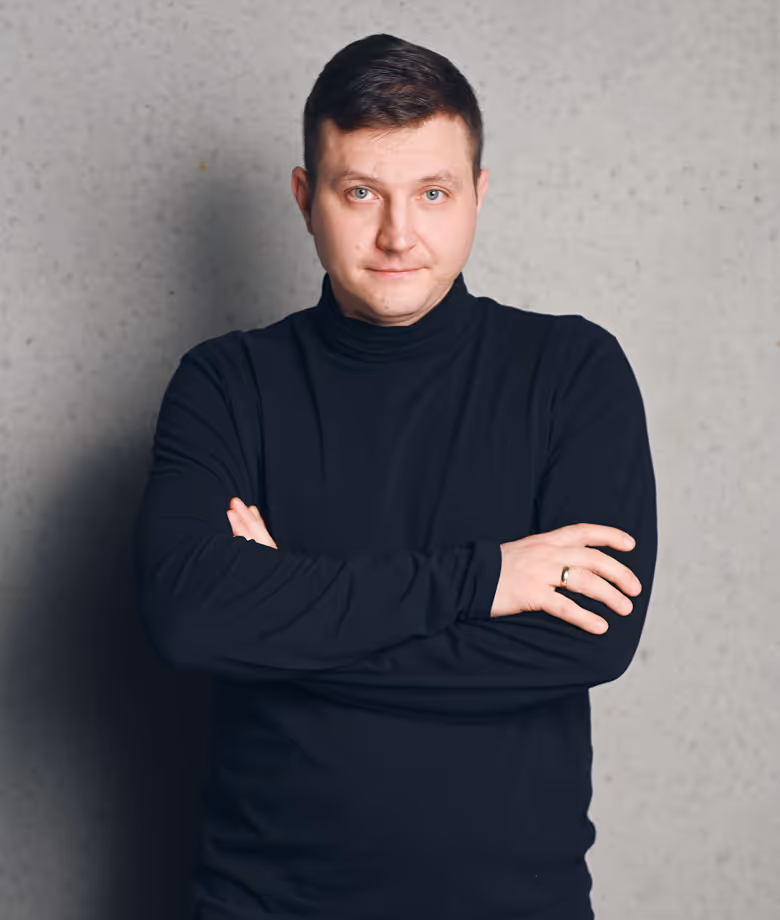  Smiling man in dark blazer in front of plain wall