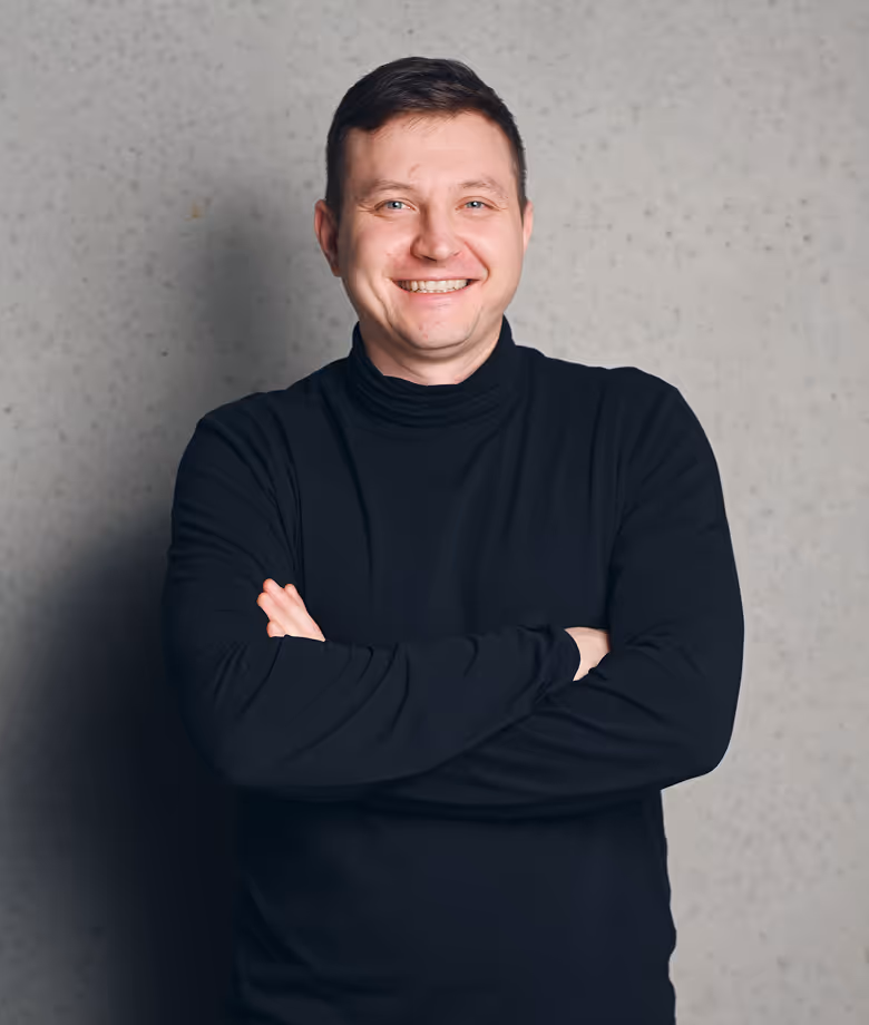  Smiling man in dark blazer in front of plain wall