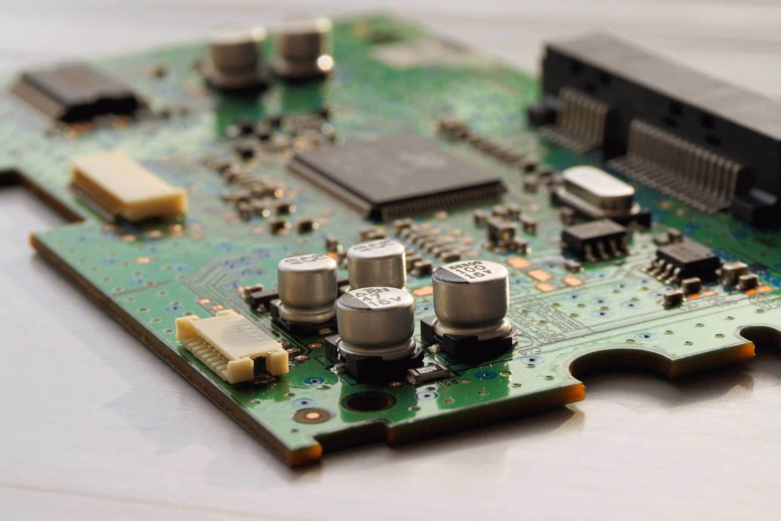 Close-up of electronic hardware design with a PCB populated by capacitors and microchips, illustrating advanced circuit board prototyping for electronic product design companies.
