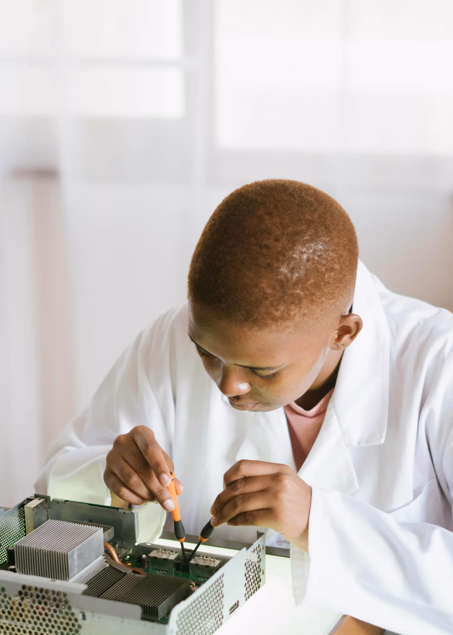 Lab technician in a white coat using precision tools to assemble and test an electronics product, showcasing hands-on hardware design, prototyping, and quality control for electronic product development companies.