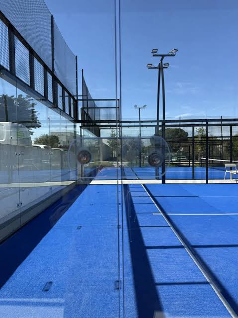 Vitrages isolants et gazon bleu d’un terrain de padel de l’hôtel ibis Montpellier