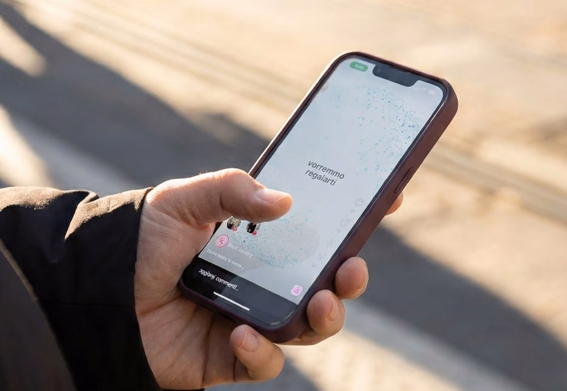 Persona che tiene in mano uno smartphone con uno schermo che mostra un messaggio in italiano 'vorremmo regalarti'.