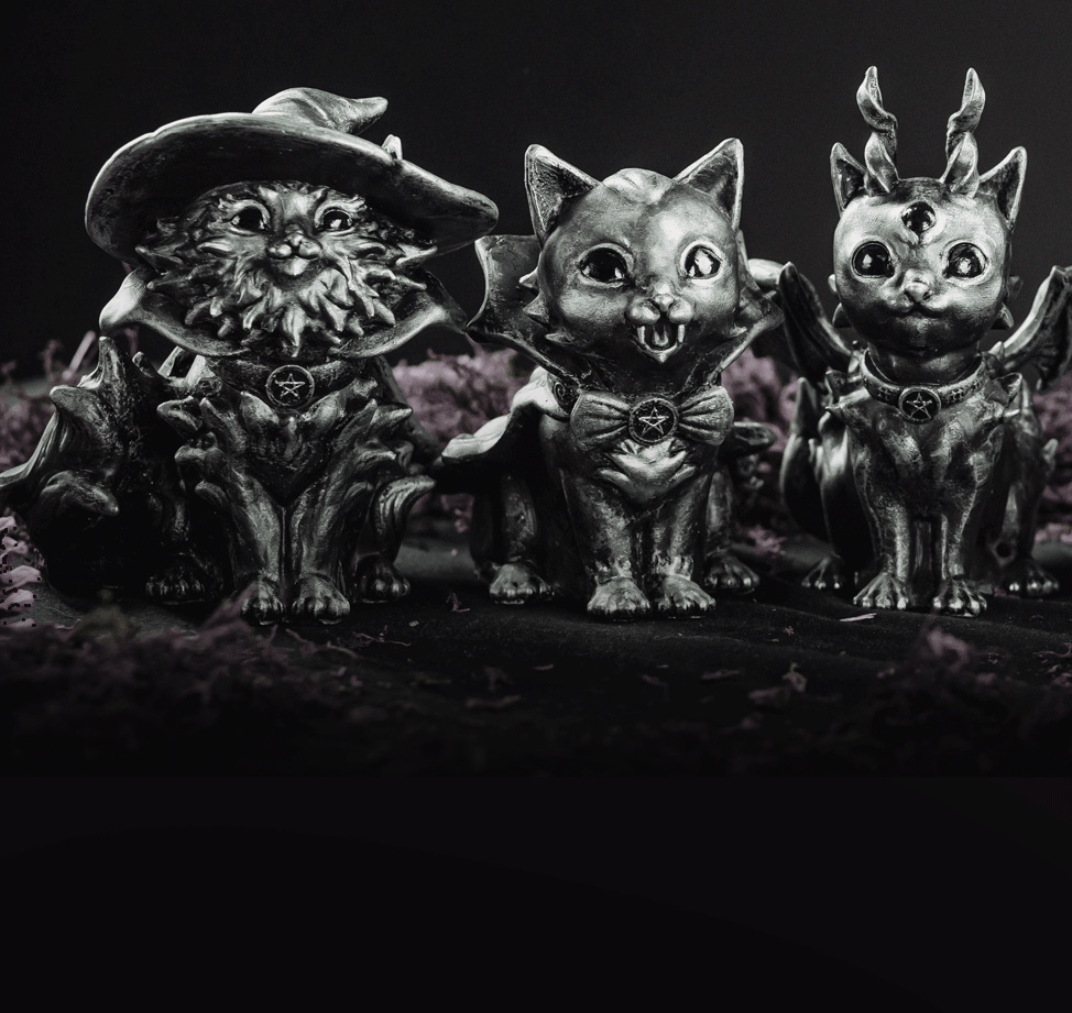 Hexenpets cat figurines with witch, vampire and antlered designs, arranged against a dark background.