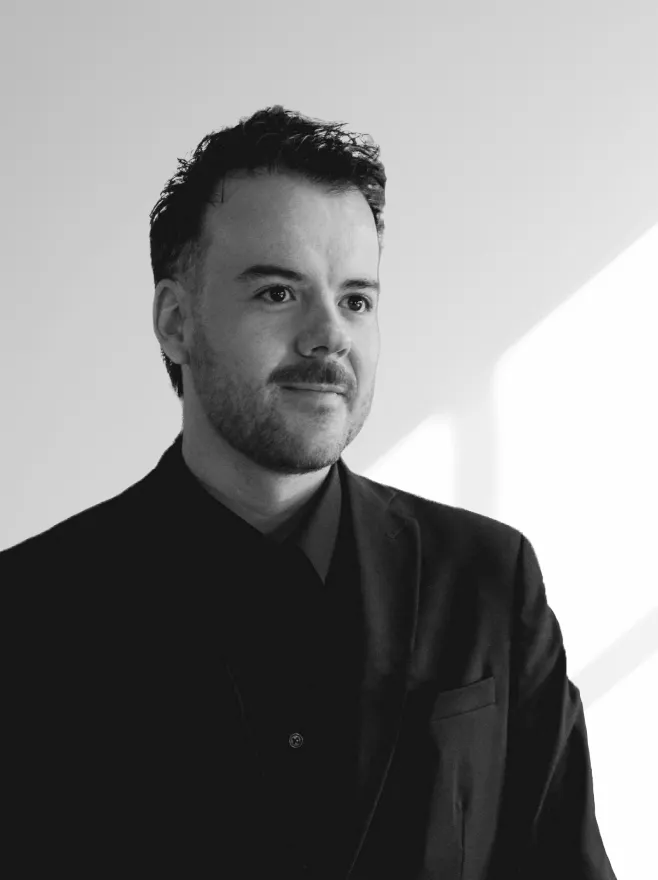 Portrait en noir et blanc de jerome vabois portant un costume sombre, regardant légèrement vers la droite avec un léger sourire.