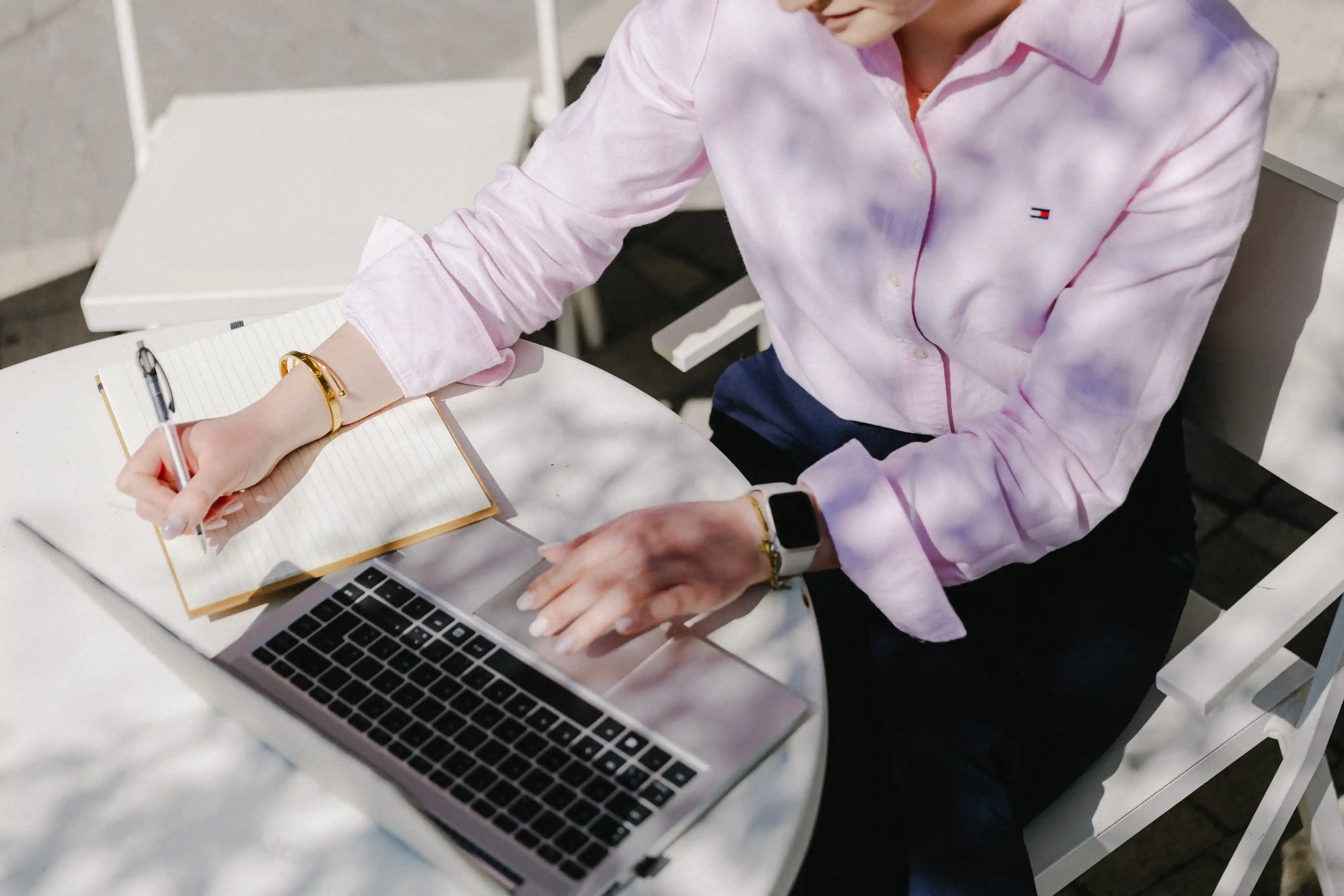 Professional taking notes while working on a laptop, representing a Legile OneView user managing legal and compliance tasks