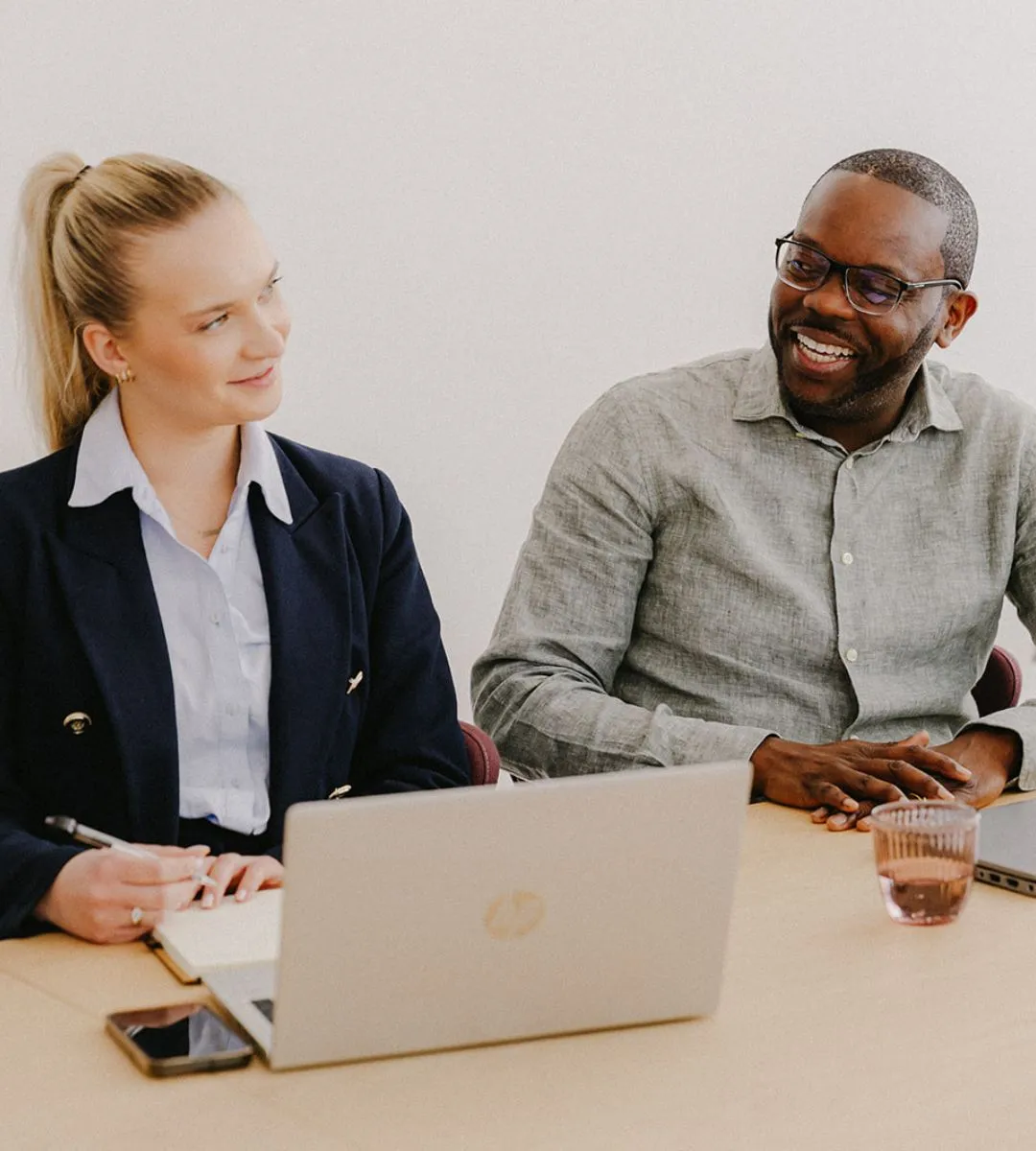 Two colleagues in conversation at a laptop during a meeting