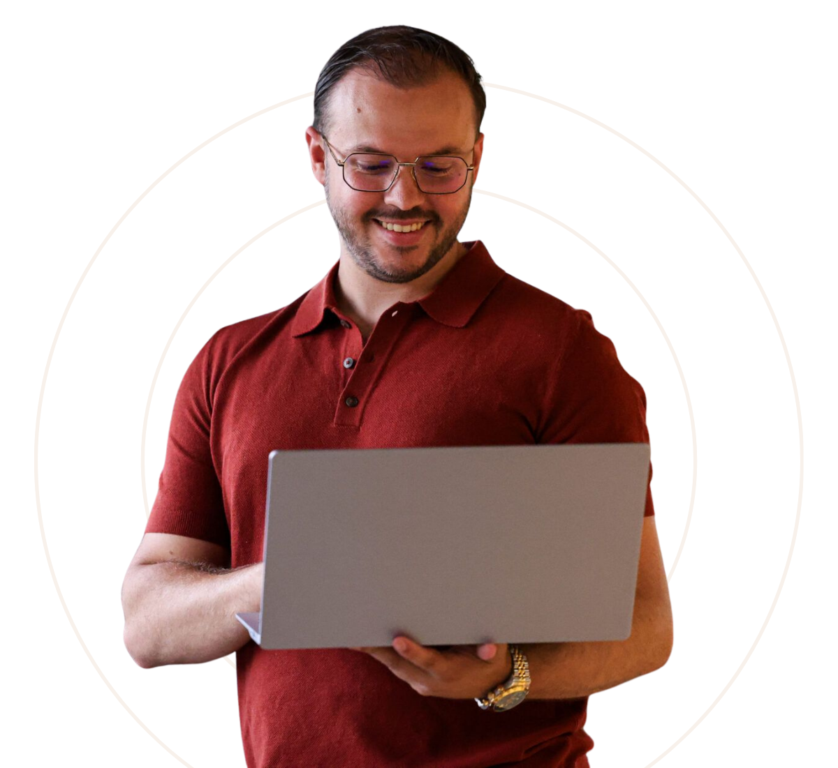 Man met bril en bordeauxrood polohemd die glimlacht terwijl hij op een laptop werkt.