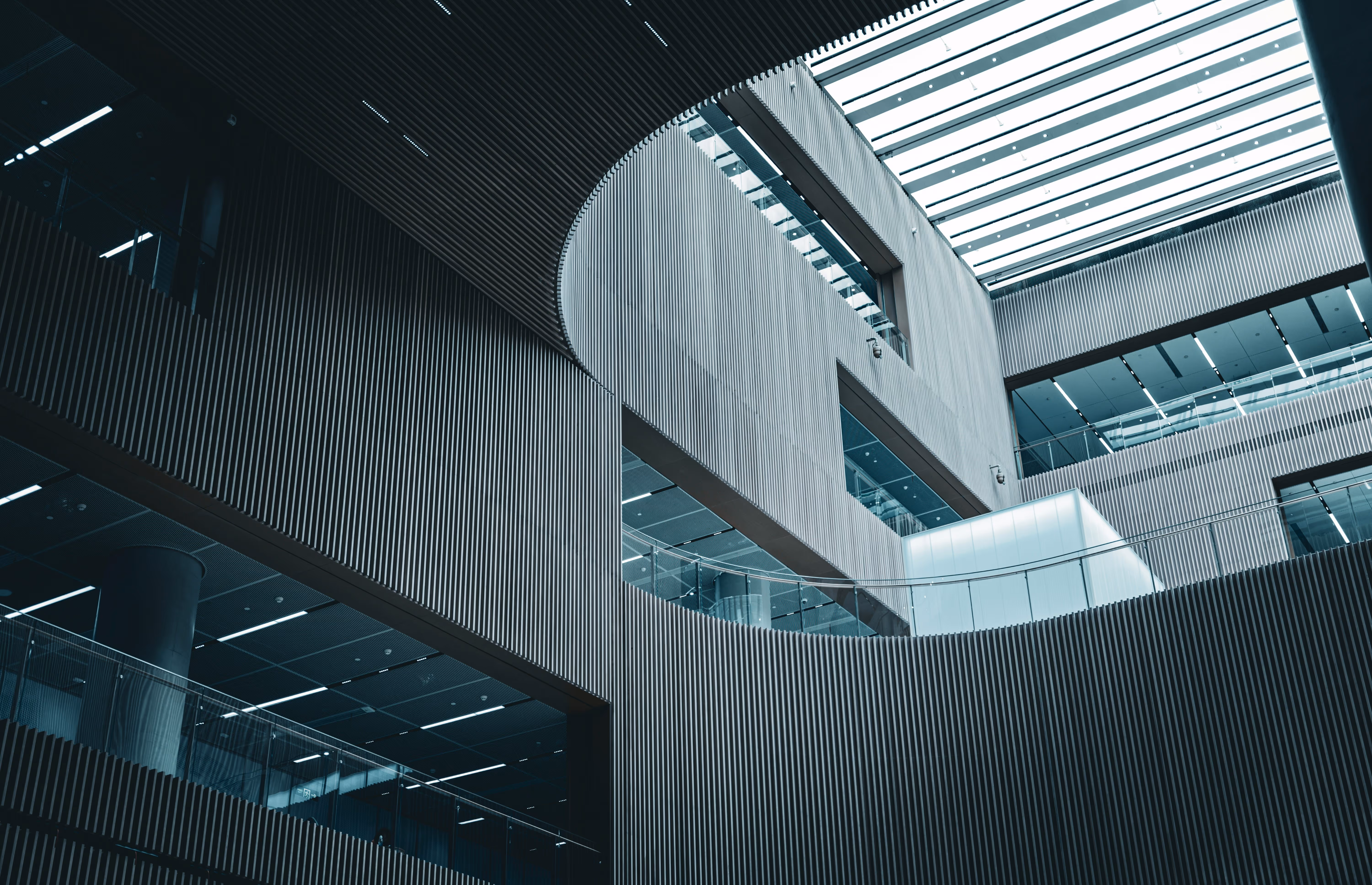 Interior view of a modern building with curved walls featuring vertical slats, large windows, and a skylight ceiling.